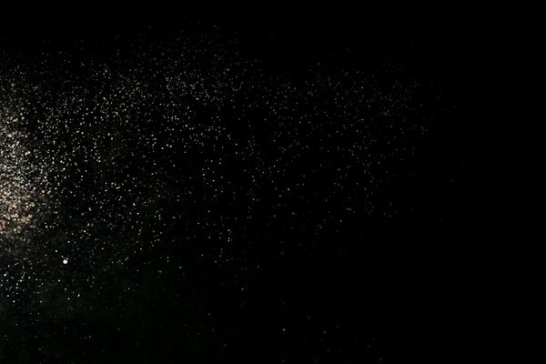 Glowing abstract particles moving upwards in a dark blue space